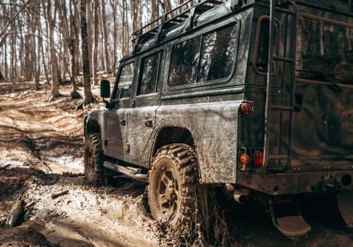 Offroad car driving through the forest road of liquid mud