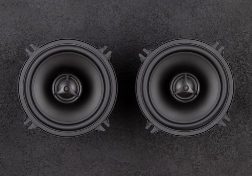 Stylish car audio acoustic round speakers on dark black background closeup